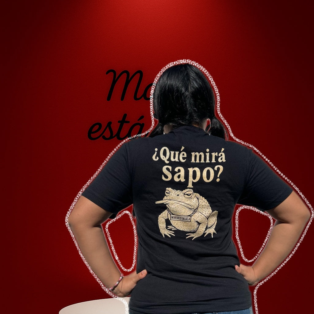 Person wearing a black t-shirt with a graphic and text on the back, standing against a red background.
