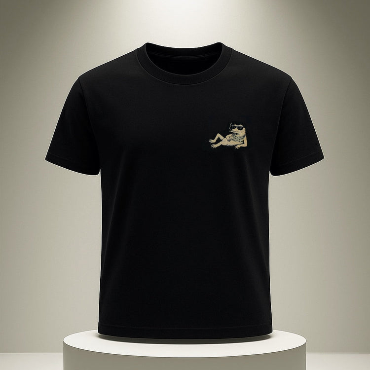 Black t-shirt with a small logo on a white pedestal against a gray background