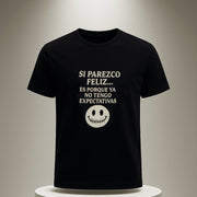 Black t-shirt with white text and smiley face on a white pedestal against a neutral background