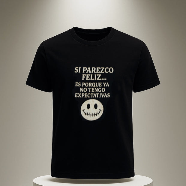 Black t-shirt with white text and smiley face on a white pedestal against a neutral background