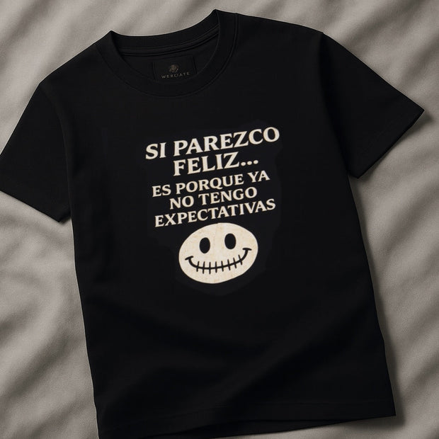 Black t-shirt with white text and smiley face on a gray fabric background