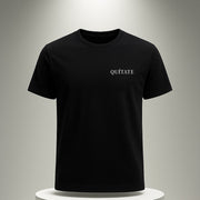 Black t-shirt with 'QUITATE' text on a white pedestal against a gray background