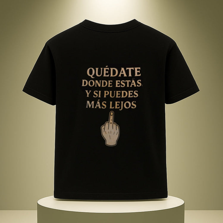 Black t-shirt with Spanish text and middle finger gesture on a white pedestal against a beige background