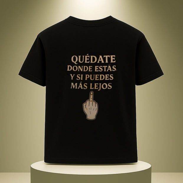 Black t-shirt with Spanish text and middle finger gesture on a white pedestal against a beige background